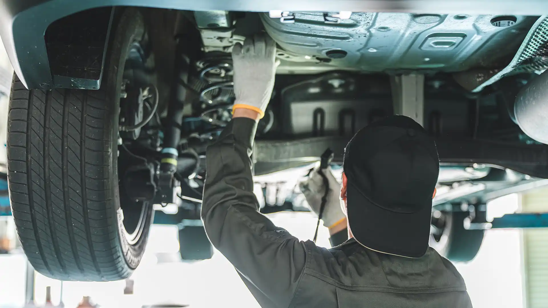 リフトアップされた車の下で作業している整備士